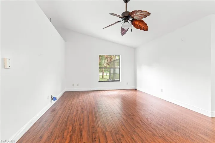 Empty room with lofted ceiling, ceiling fan, and hardwood / wood-style floors