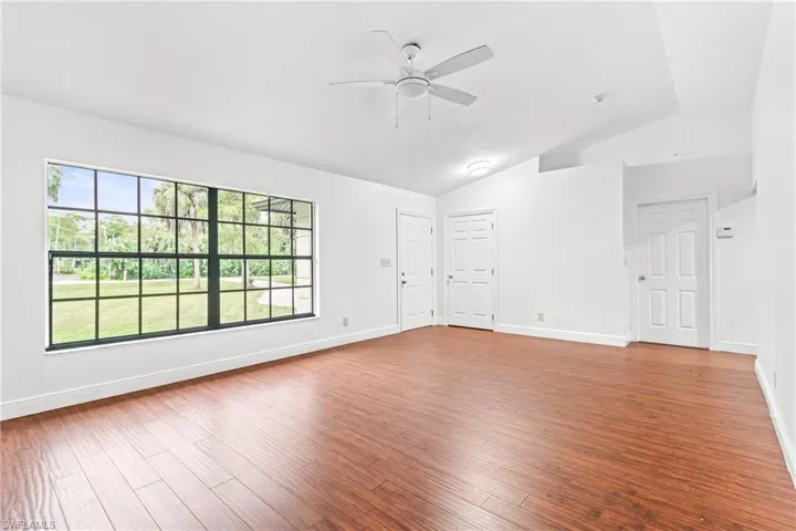Unfurnished room with lofted ceiling, ceiling fan, and hardwood / wood-style floors
