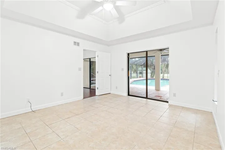 Tiled empty room featuring a tray ceiling and ceiling fan
