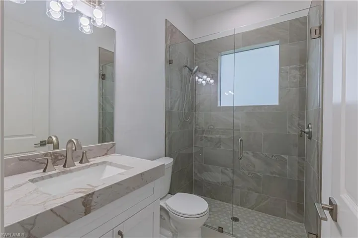 Full bathroom with toilet, a stall shower, and vanity