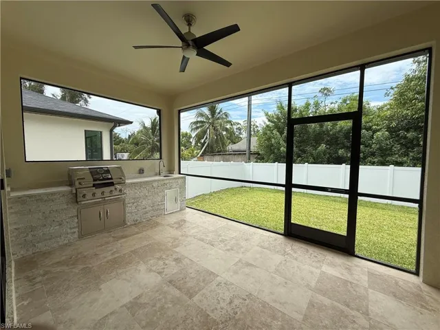 Unfurnished sunroom with ceiling fan and exterior kitchen