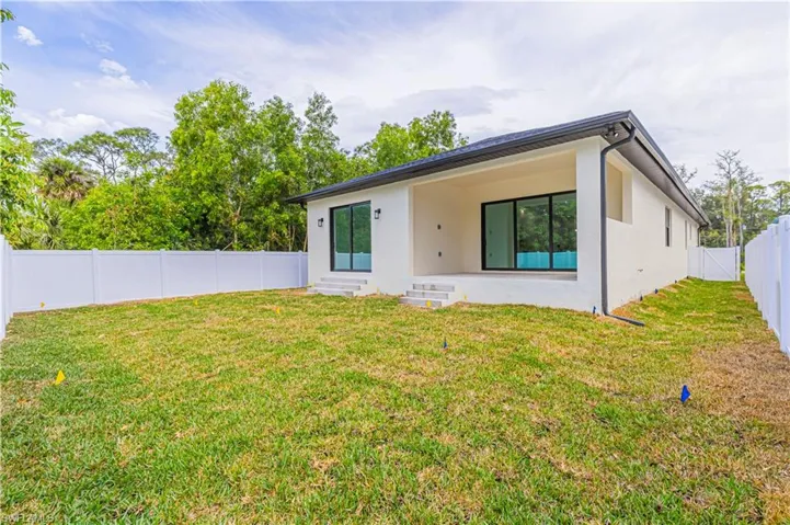 Rear view of house featuring a fenced backyard, a lawn, stucco siding, and entry steps