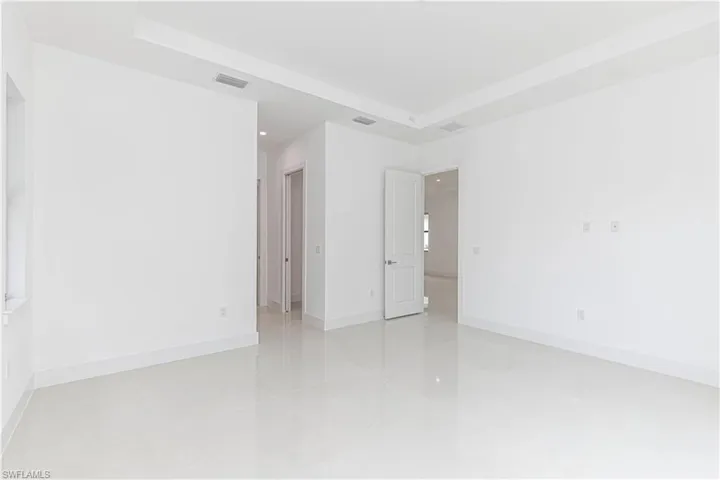 Unfurnished room featuring a tray ceiling, baseboards, and visible vents