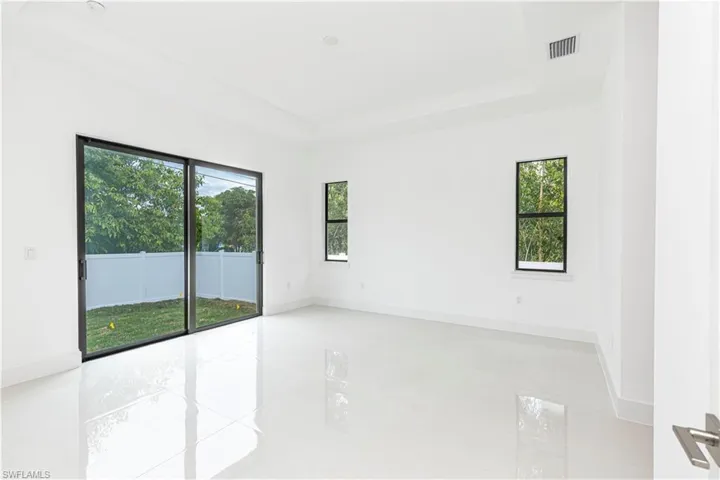 Unfurnished room featuring baseboards, a tray ceiling, visible vents, and a healthy amount of sunlight
