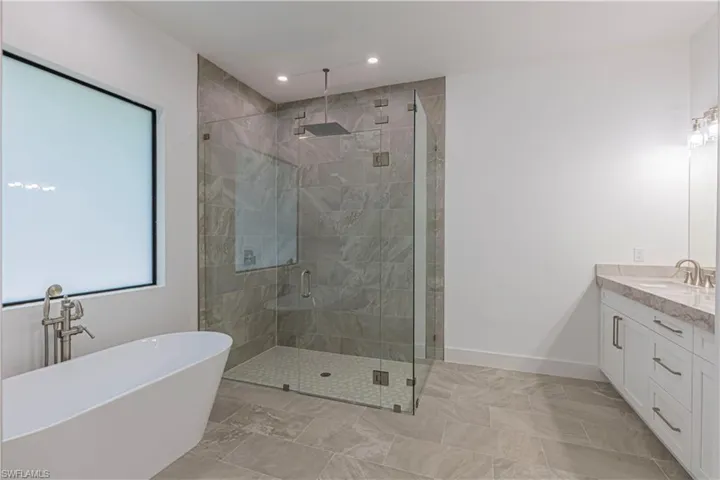 Full bathroom featuring baseboards, recessed lighting, vanity, a stall shower, and a freestanding bath