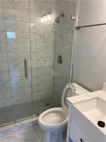 Bathroom with vanity, a shower stall, and a textured wall