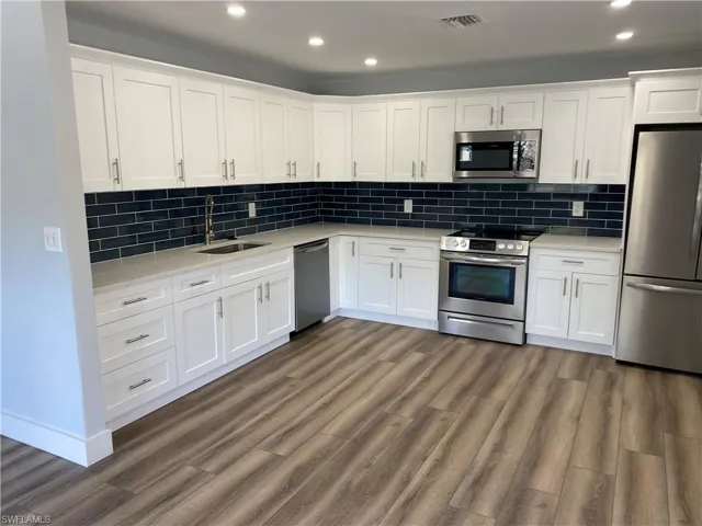 Kitchen featuring stainless steel appliances, white cabinets, tasteful backsplash, light stone countertops, and recessed lighting