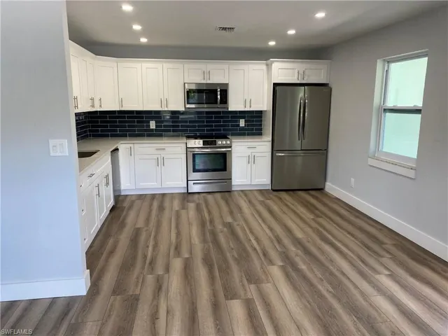 Kitchen with white cabinets, stainless steel appliances, tasteful backsplash, and recessed lighting