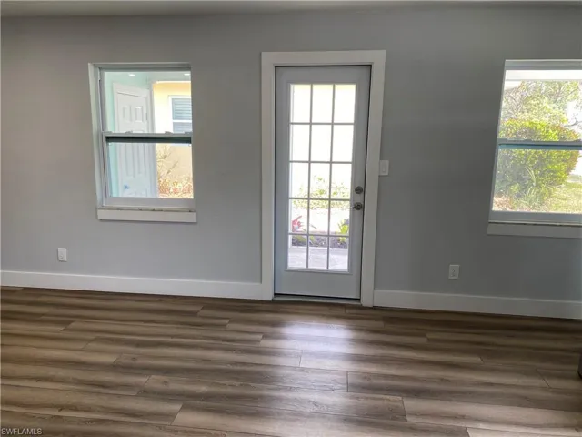 Doorway to outside featuring baseboards and wood finished floors