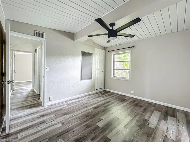 Empty room featuring wood finished floors, ceiling fan, wooden ceiling, and a textured wall
