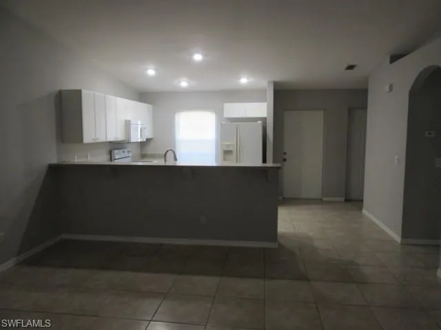 Kitchen featuring white cabinetry, light countertops, and a breakfast bar