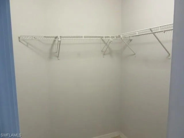 Walk-in closet featuring white wire shelving and hanging rods