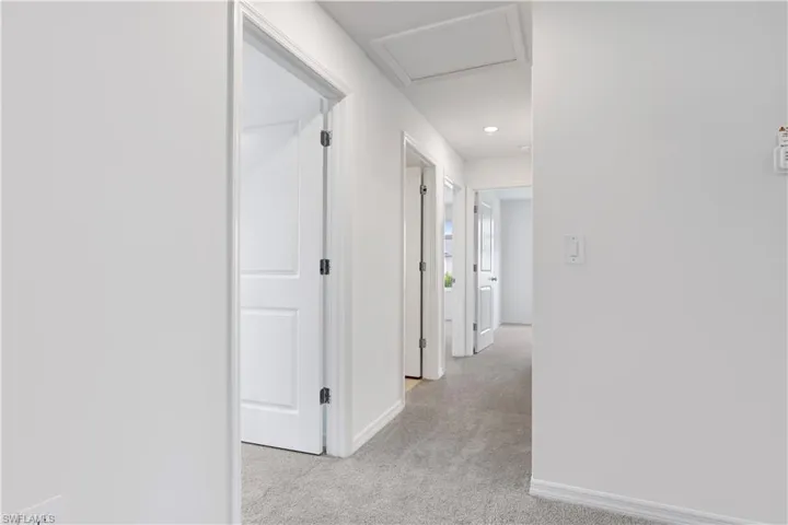 Carpeted hallway with white walls and trim, recessed lighting, and multiple paneled interior doors