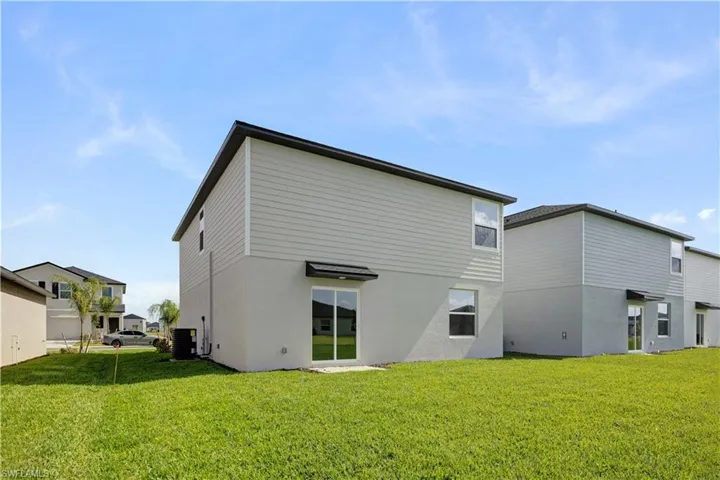 Rear exterior featuring a two-story design with horizontal siding and stucco finishes, multiple windows, and a sliding glass door