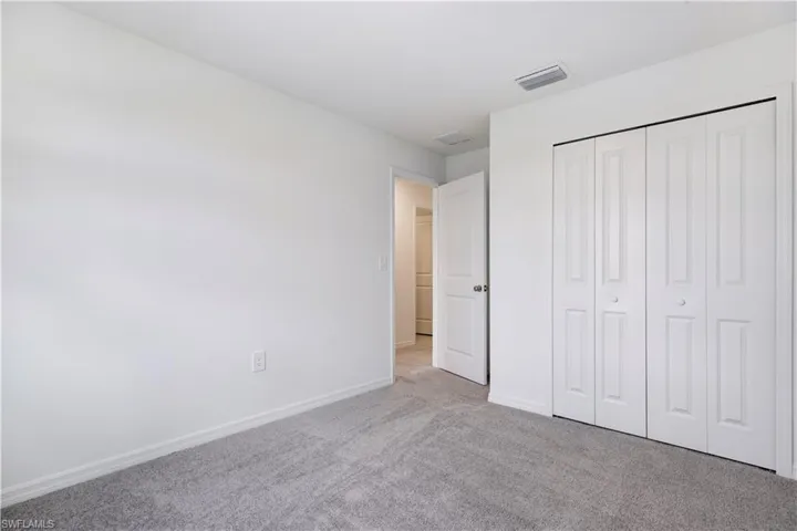 Neutral tone walls with gray carpeting, featuring a bi-fold closet with white paneled doors, and white trim throughout