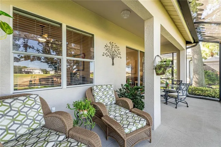 Lanai with wicker chairs and cushions, windows, sliding doors, overhang, plants, table with chairs, heavy duty screening.