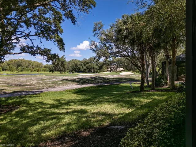 View from the lanai of trees in back yard and grass growing on the private golf course approximately 100 yards from the green on the 12th hole.