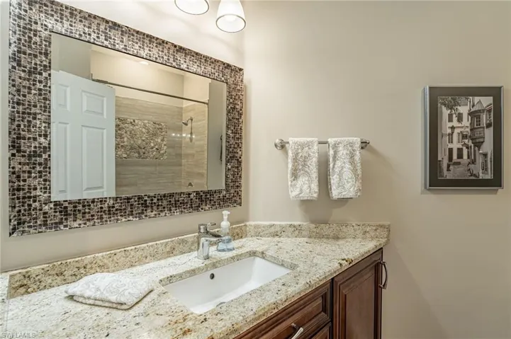 Guest bathroom with sink, mirror, granite counter tops, lights, picture, self closing drawers & doors, drop down drawer in front of sink and towels.