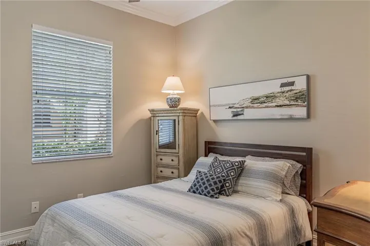 Guest Bedroom with a window, corner chest, lamp, bed, crown molding, fan, and a night table on the right.
