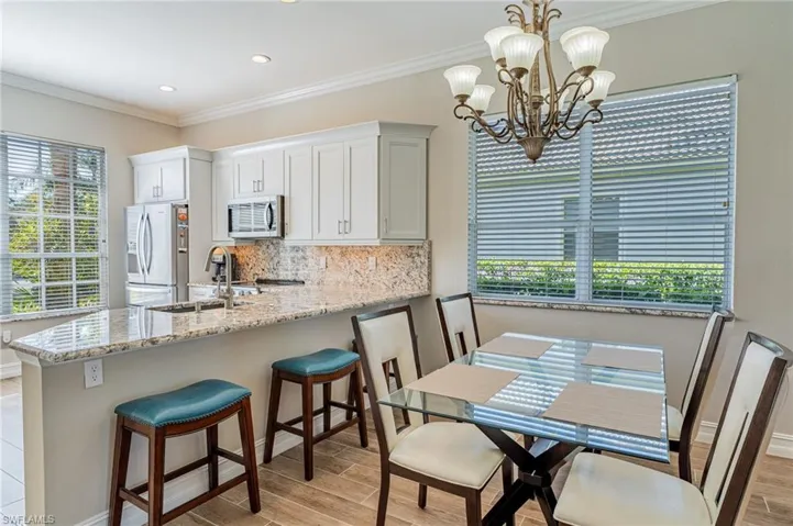 Three stools, dining room table and chairs, windows with Granite o  sills and crown molding adding to the brightness of the home.