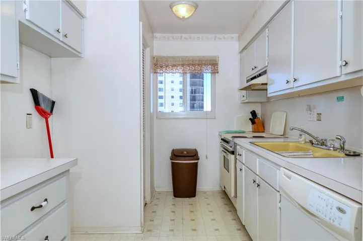 Kitchen with under cabinet range hood, light floors, dishwasher, light countertops, and a sink