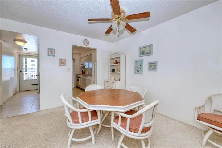 Dining space with light tile patterned floors, light colored carpet, a textured ceiling, and ceiling fan