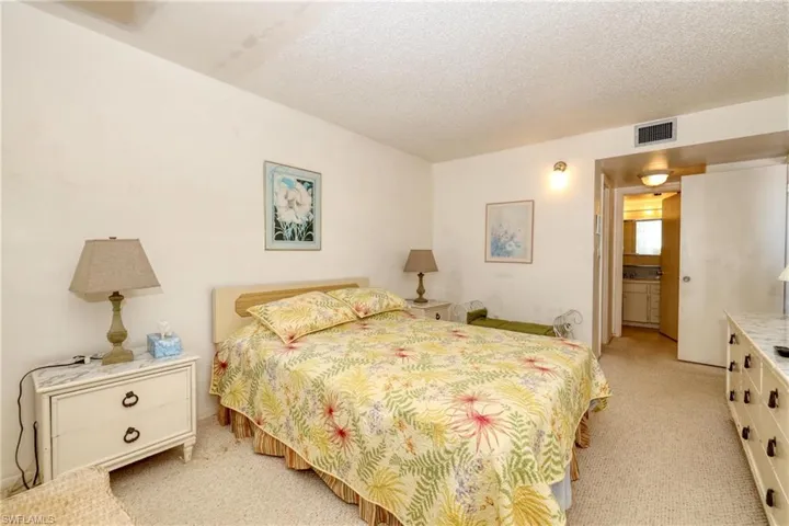 Bedroom featuring visible vents, a textured ceiling, and light colored carpet