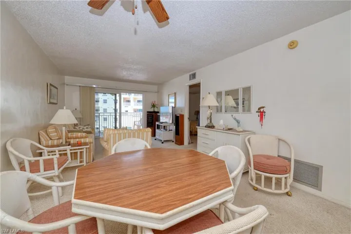 Dining room featuring a textured ceiling, light colored carpet, visible vents, and ceiling fan