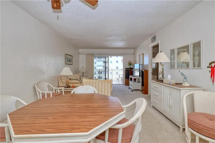 Dining area featuring visible vents, light colored carpet, a textured ceiling, and a ceiling fan