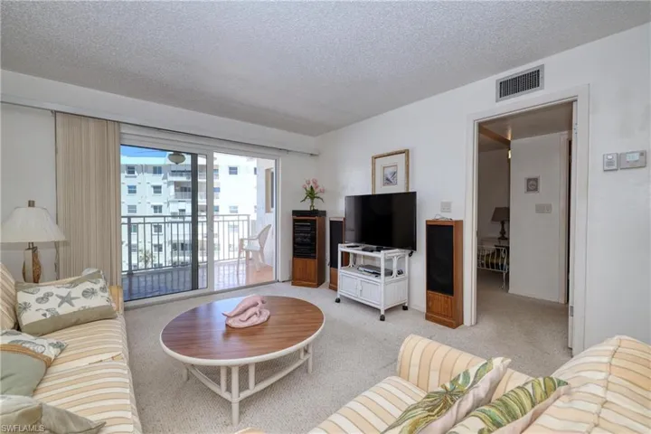 Living room featuring a textured ceiling, visible vents, and light carpet