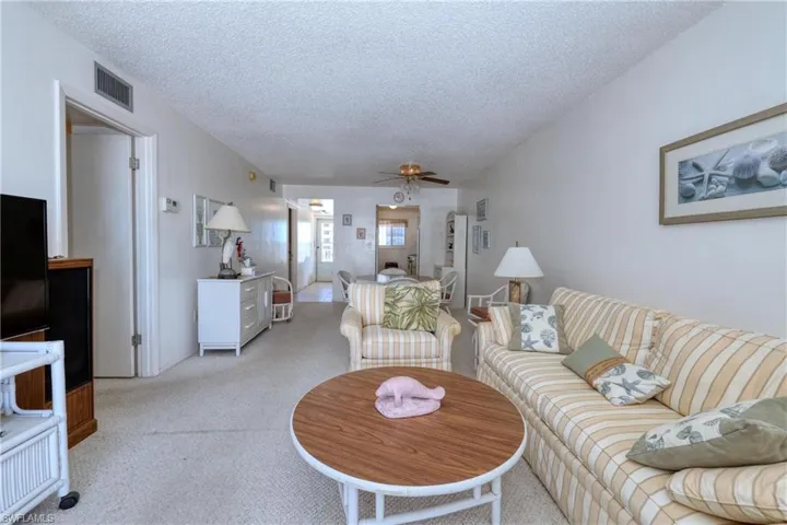 Living area featuring ceiling fan, a textured ceiling, visible vents, and light carpet