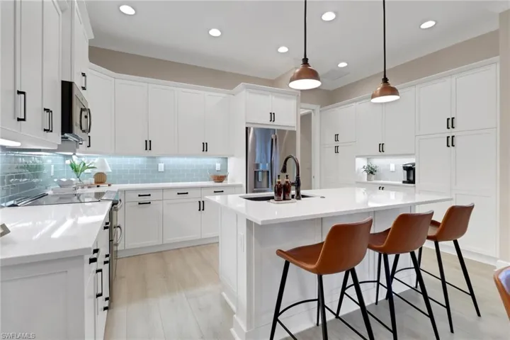 Kitchen with backsplash, a center island with sink, appliances with stainless steel finishes, light wood-style flooring, and recessed lighting