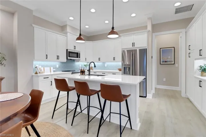 Kitchen featuring backsplash, decorative light fixtures, light wood-type flooring, white cabinets, and recessed lighting