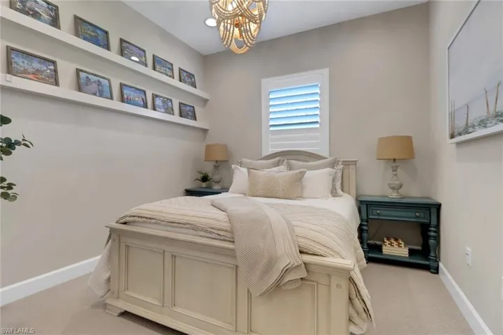 Bedroom featuring light colored carpet and a chandelier
