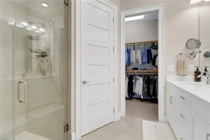 Bathroom featuring vanity, a shower stall, a spacious closet, and light tile patterned floors