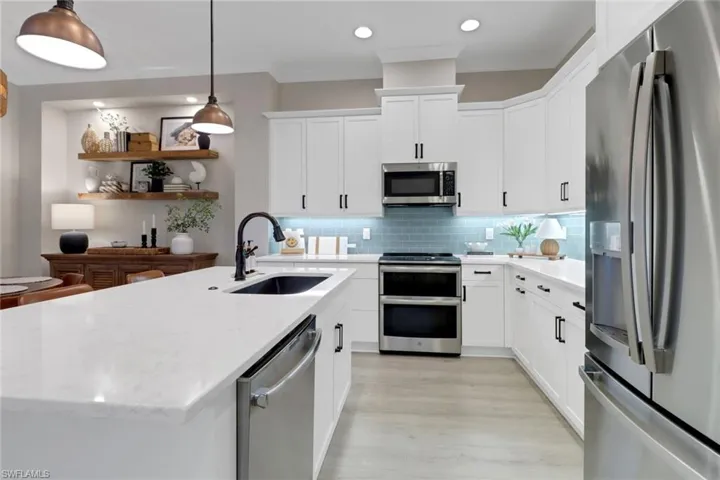 Kitchen featuring stainless steel appliances, tasteful backsplash, a center island with sink, white cabinetry, and recessed lighting