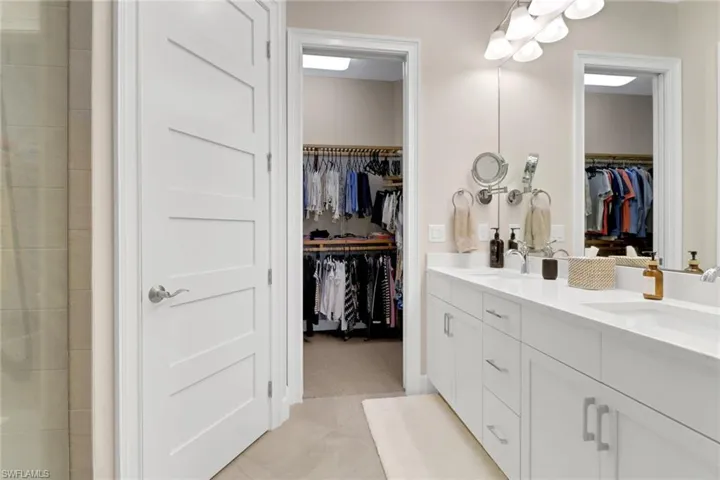 Bathroom featuring double vanity, a walk in closet, and light tile patterned flooring