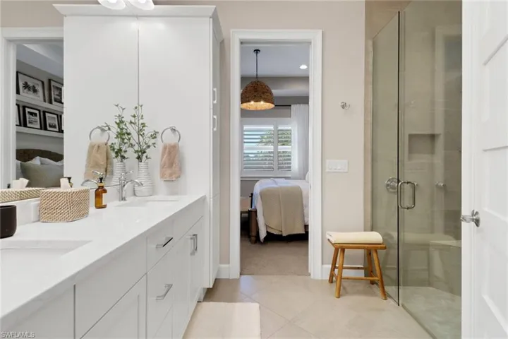 Full bath featuring ensuite bath, double vanity, a shower stall, and light tile patterned flooring