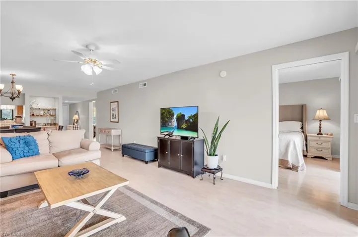 Living room featuring ceiling fan with notable chandelier and light hardwood / wood-style floors