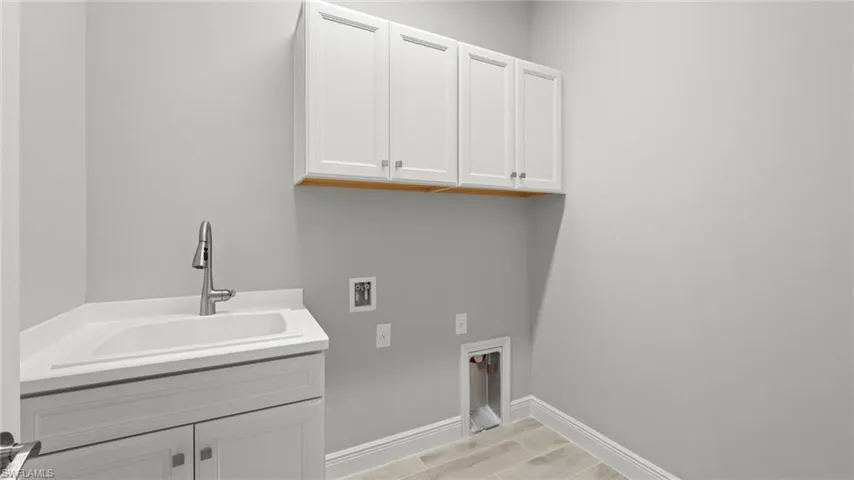 Clothes washing area featuring sink, washer hookup, and cabinets