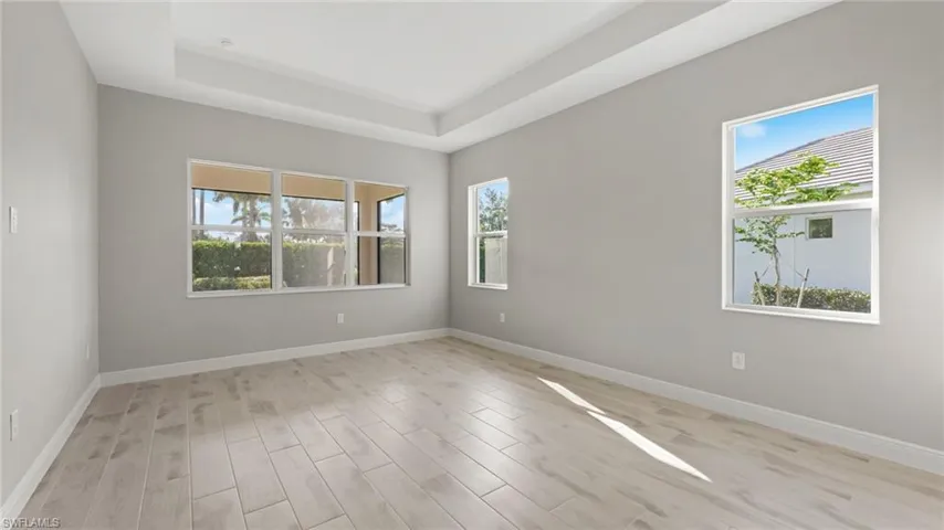 Empty room with light hardwood / wood-style floors and a raised ceiling