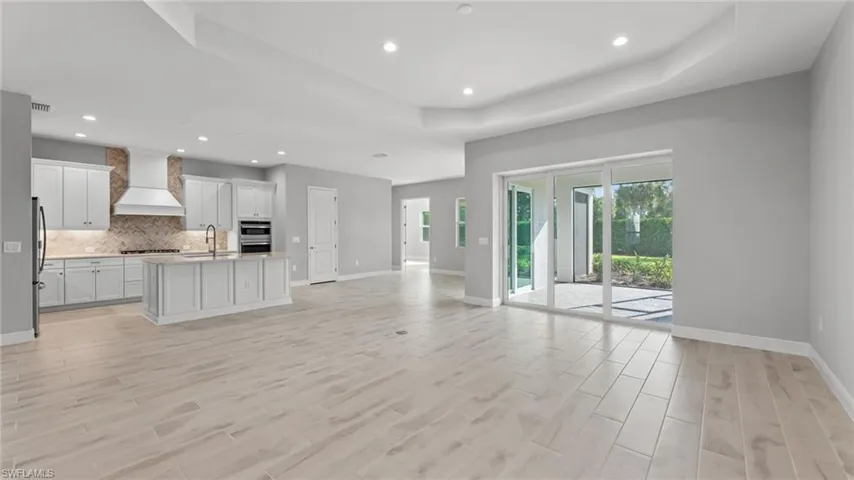 Unfurnished living room with sink, light hardwood / wood-style flooring, and a raised ceiling