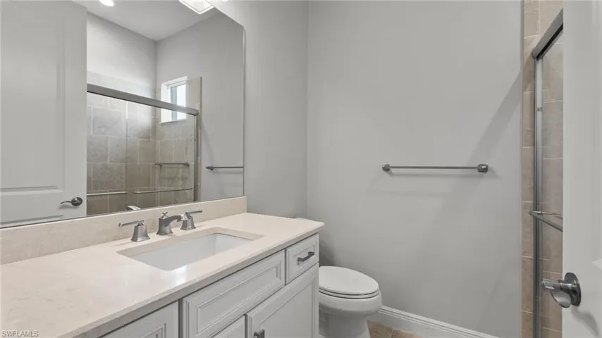 Bathroom featuring a shower with shower door, oversized vanity, and toilet