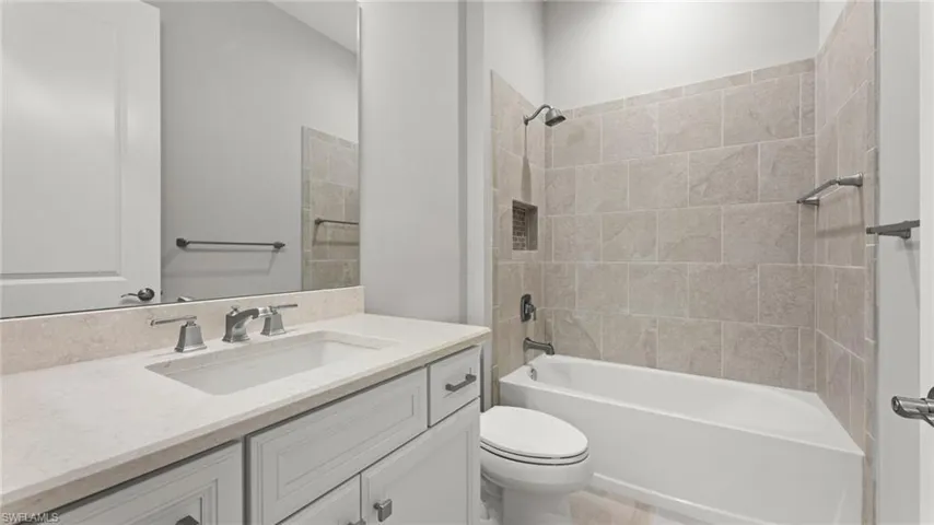 Full bathroom featuring tile flooring, tiled shower / bath combo, vanity, and toilet