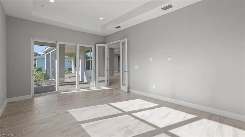 Spare room with a tray ceiling and light wood-type flooring