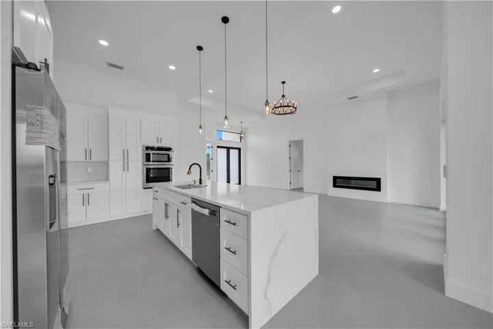 Kitchen with white cabinetry, concrete flooring, light stone countertops, stainless steel appliances, and recessed lighting