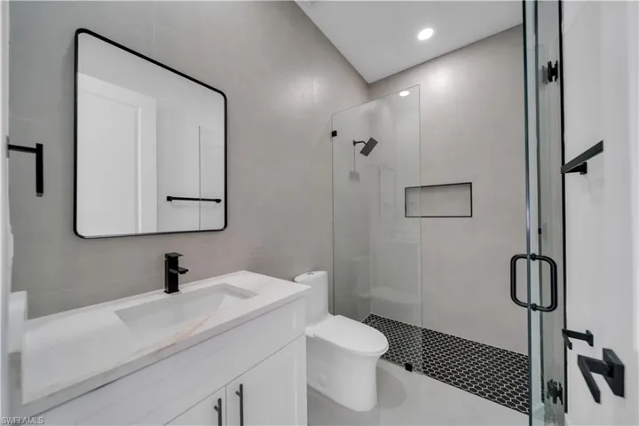 Full bathroom featuring tile walls, a shower stall, vanity, and recessed lighting