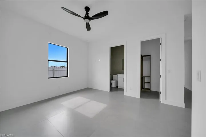 Unfurnished bedroom featuring ensuite bath, a ceiling fan, and concrete flooring