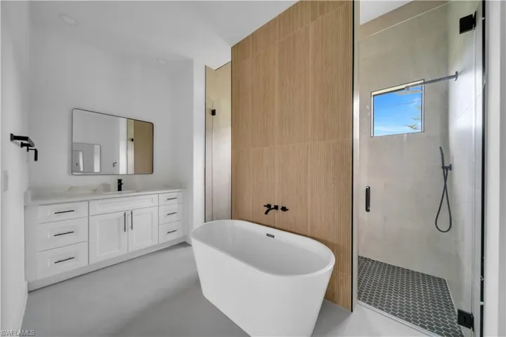 Full bathroom with a freestanding tub, a stall shower, and vanity