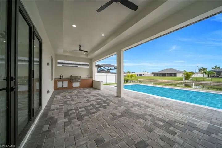 View of pool featuring an outdoor kitchen, a patio, a ceiling fan, and a residential view